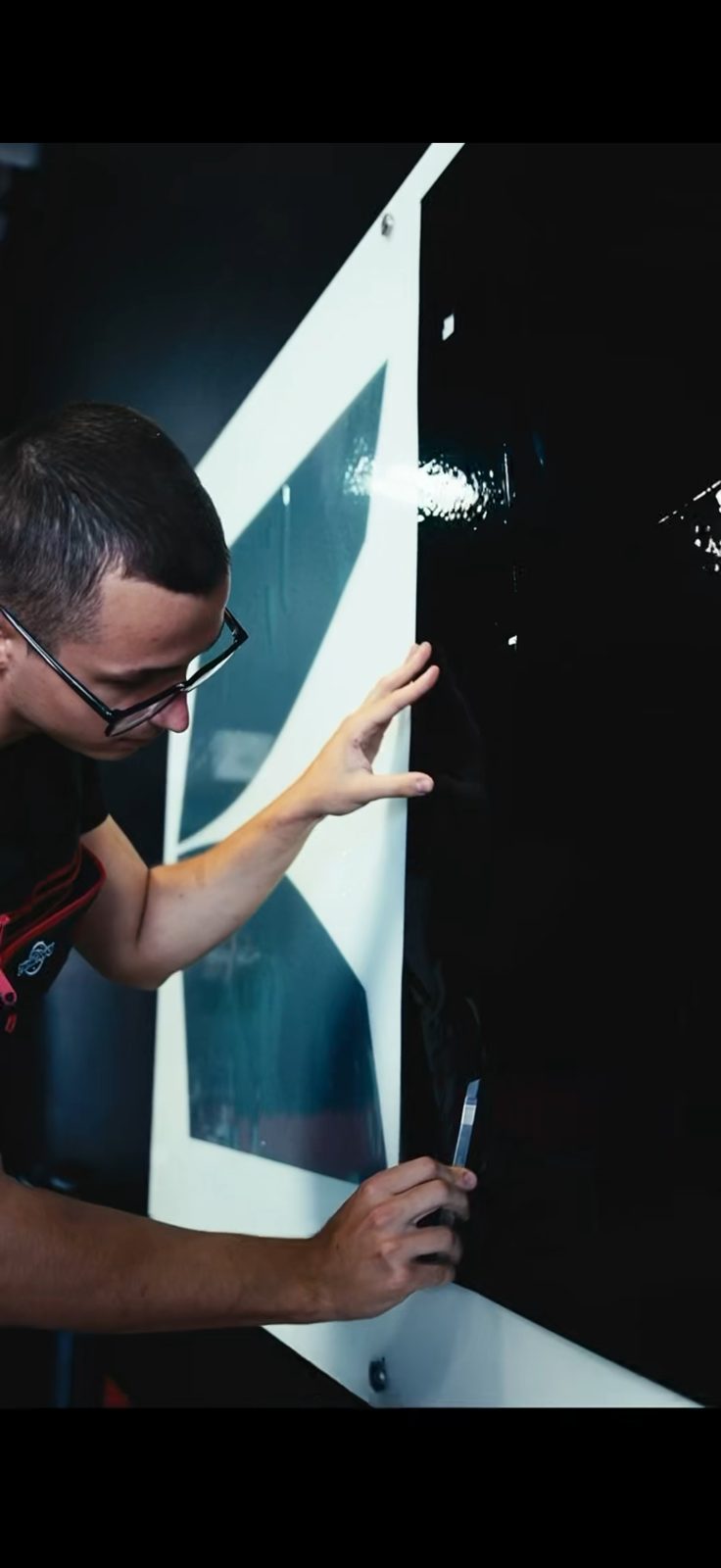 Technician inspecting window film against a light panel