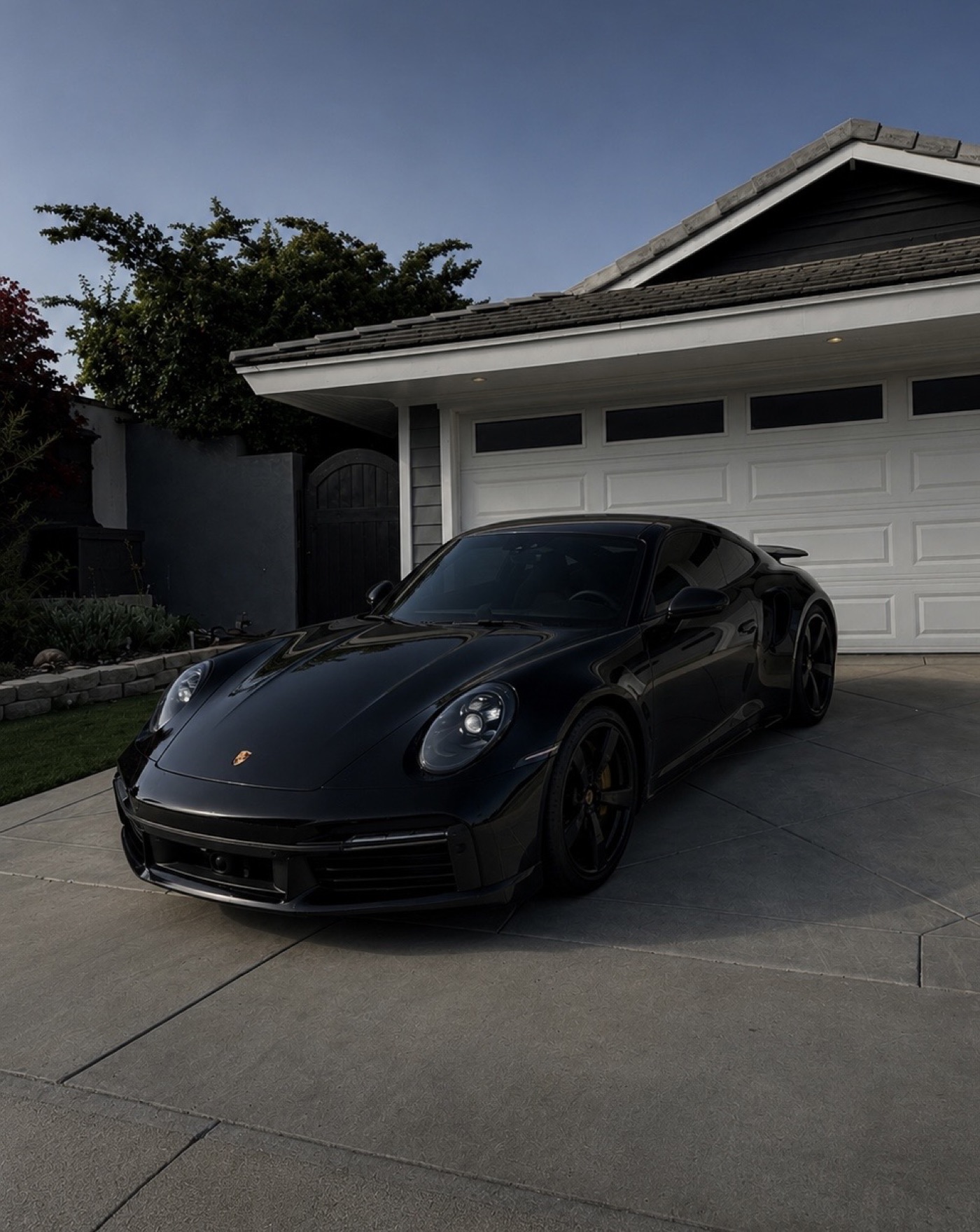 Black Porsche 911 with dark tint in a driveway